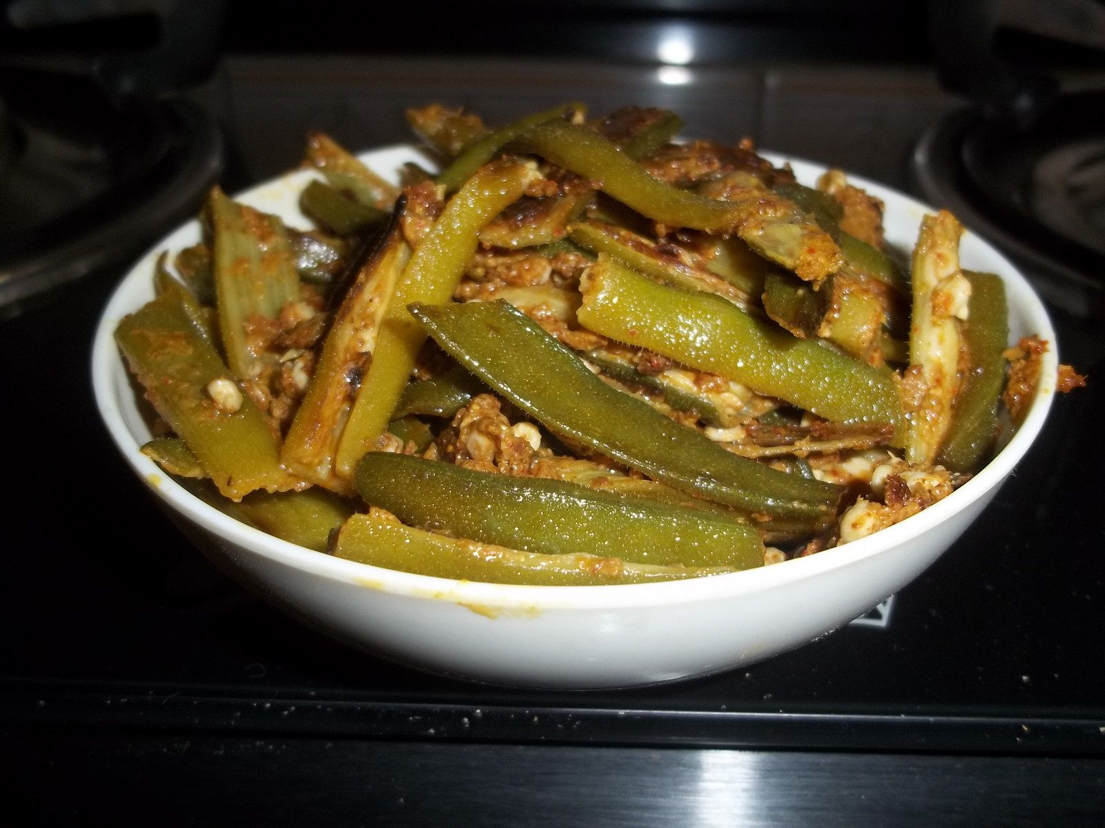 Bhindi masala (okra) in a white bowl on a dark counter