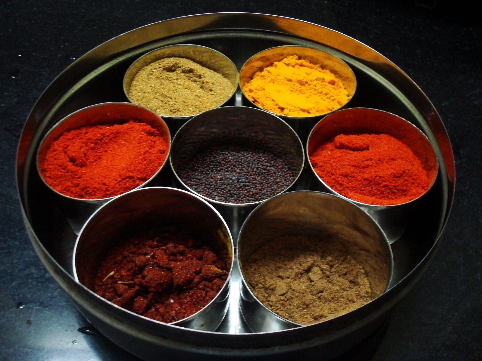 Top-down view of a seven-compartment Indian spice box